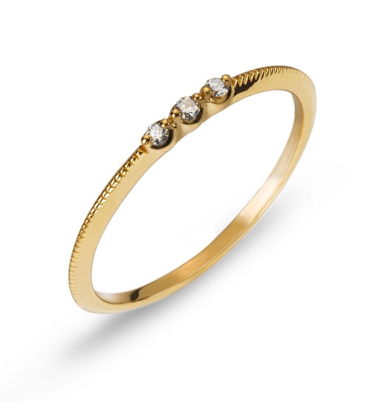 Bague en or avec trois petits diamants sertis sur l'anneau, sur fond blanc.