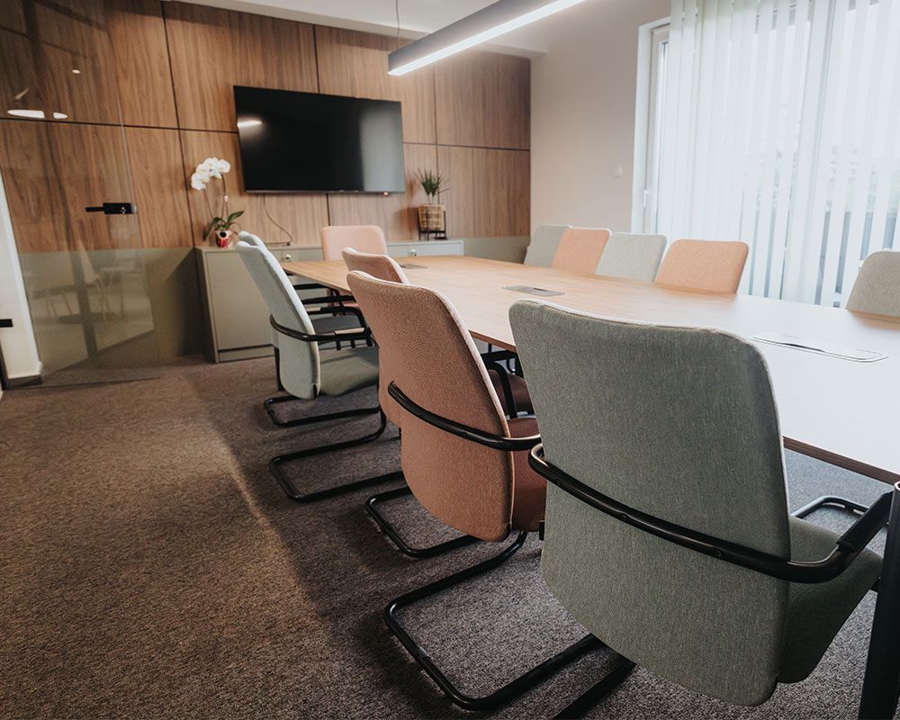 A conference room with a long table and chairs and a flat screen tv.