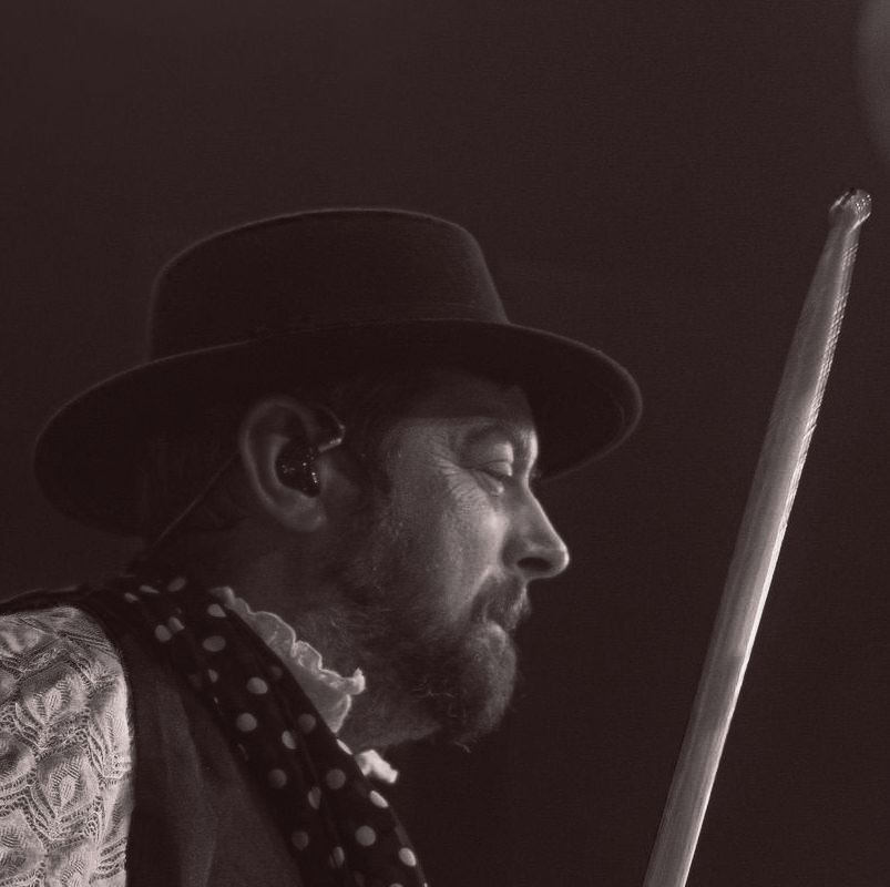 Mike Francis performing as Mick Fleetwood with Tell Me Lies - Fleetwood Mac Tribute Man in hat playing drums, black and white.