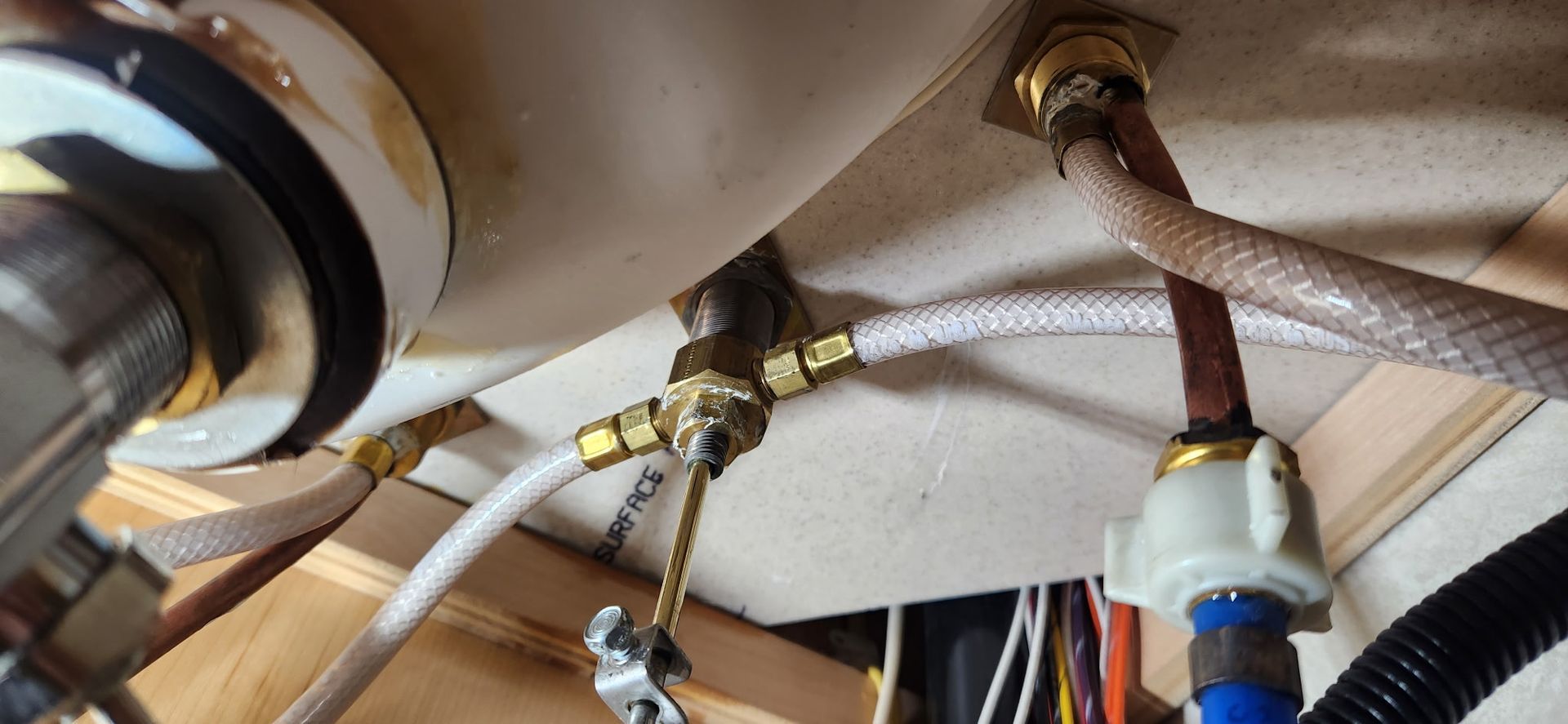 Under-sink plumbing with hoses, fittings, and valves connected beneath a sink
