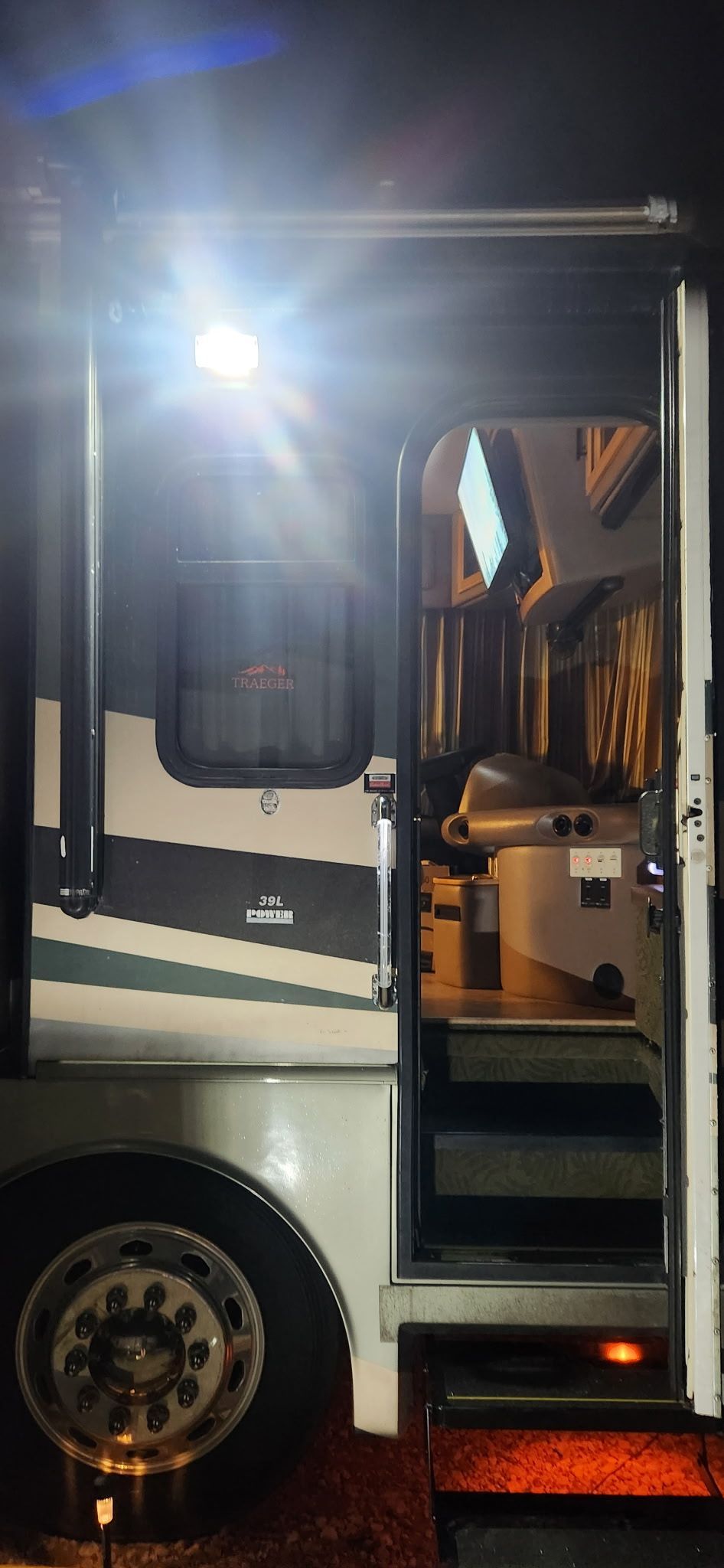 White truck cab with open door at night, bright light glare, showing interior and wheel.