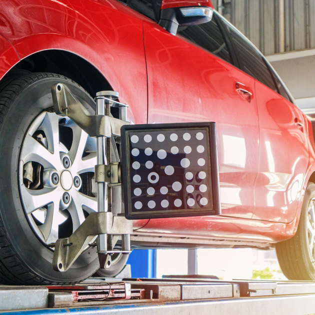UK Select Accident Repair Centres | A red car is being adjusted by a machine in a garage.
