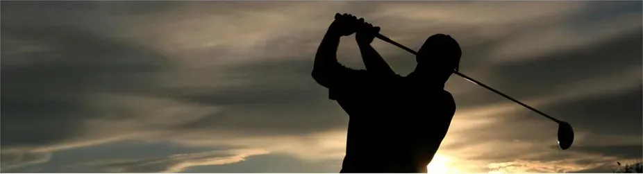 A silhouette of a person swinging a golf club at sunset.
