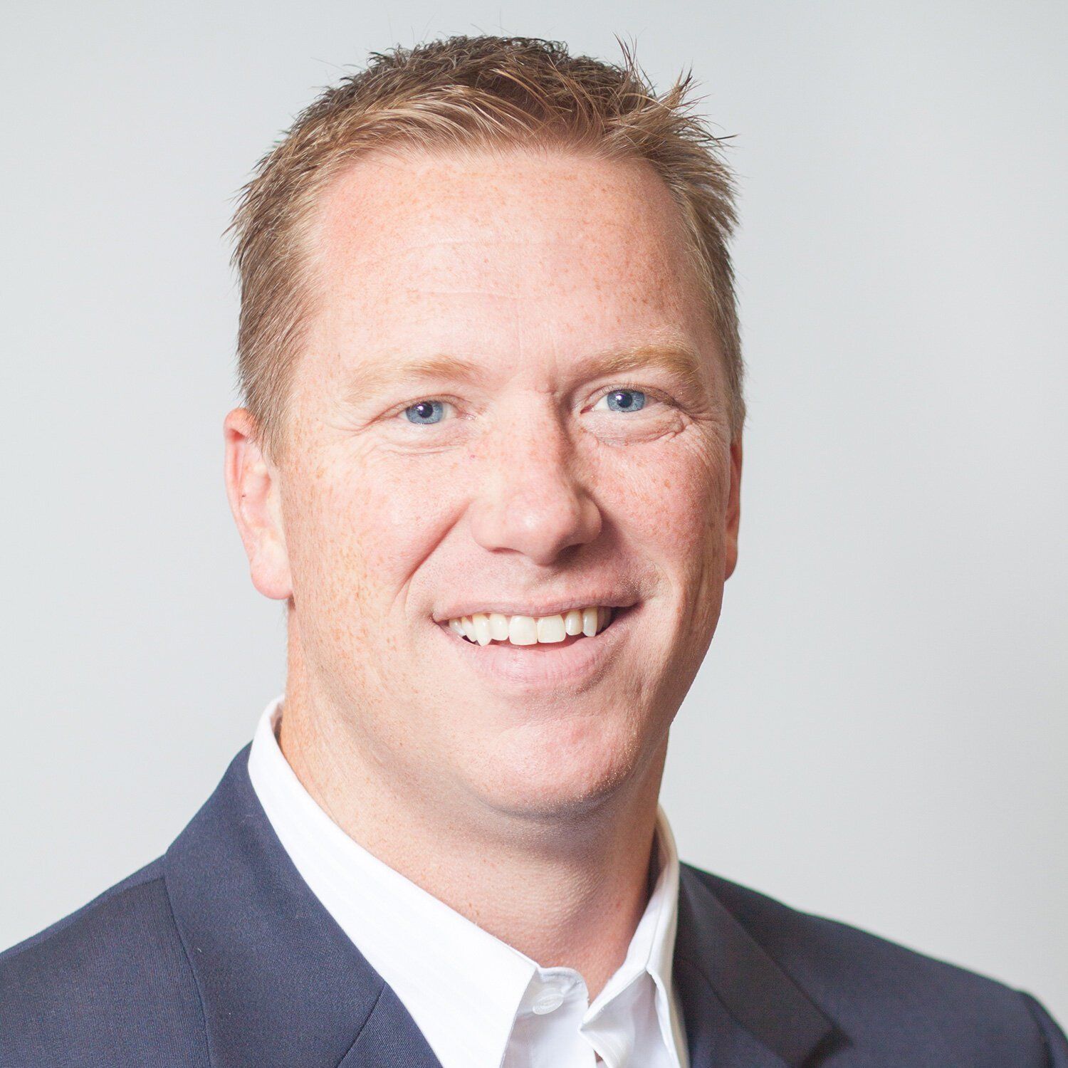 Headshot of an Noblesville business man in a navy suit and white shirt against a light gray background