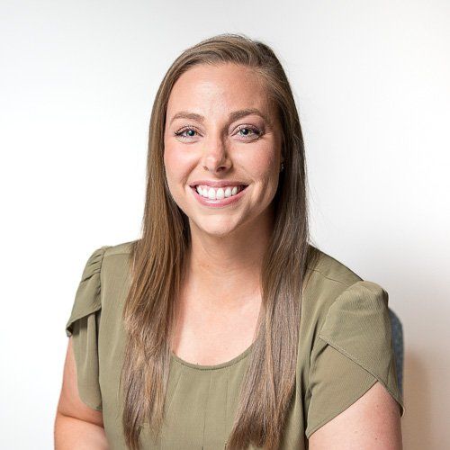 Headshot of a smiling woman chiropractor in Carmel Indiana in an olive-green top against a white background