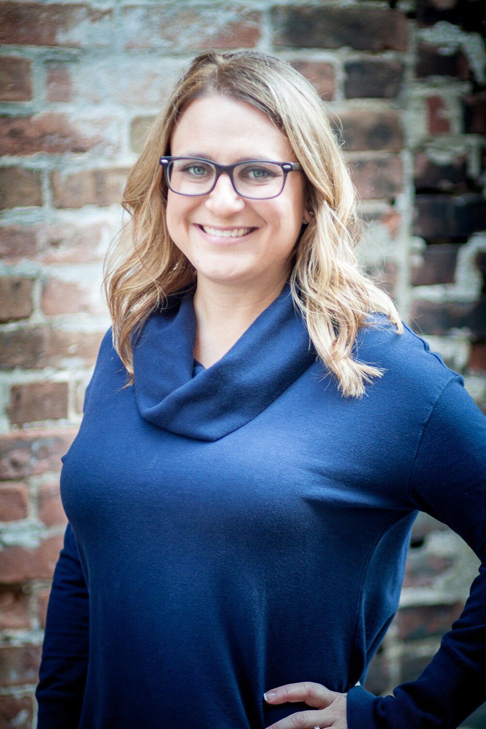 Headshot of a Westfield Indiana teacher smiling in a blue sweater standing against a brick wall