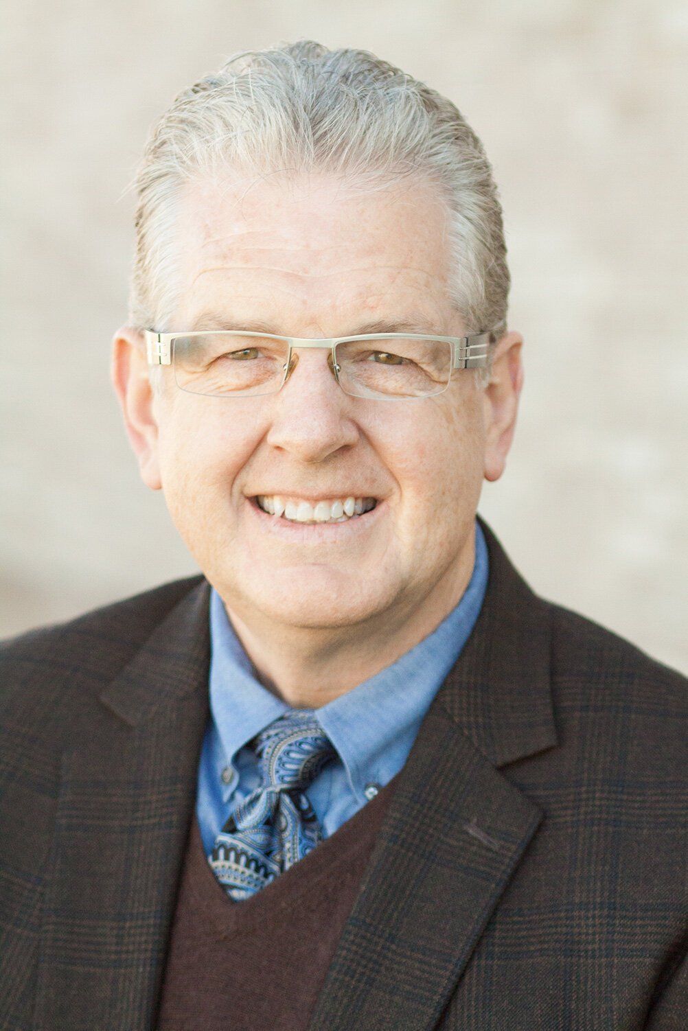 Headshot of a Fishers Indiana Chiropractor in glasses and suit jacket against a light background