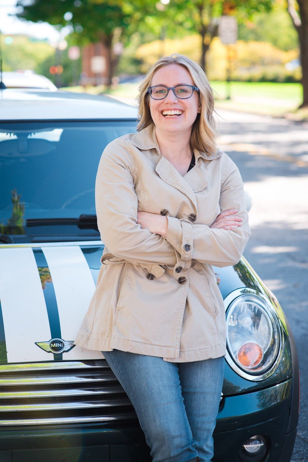 Marketing Agency owner Kristin Madeja leaning against a dark green car on a sunny street.