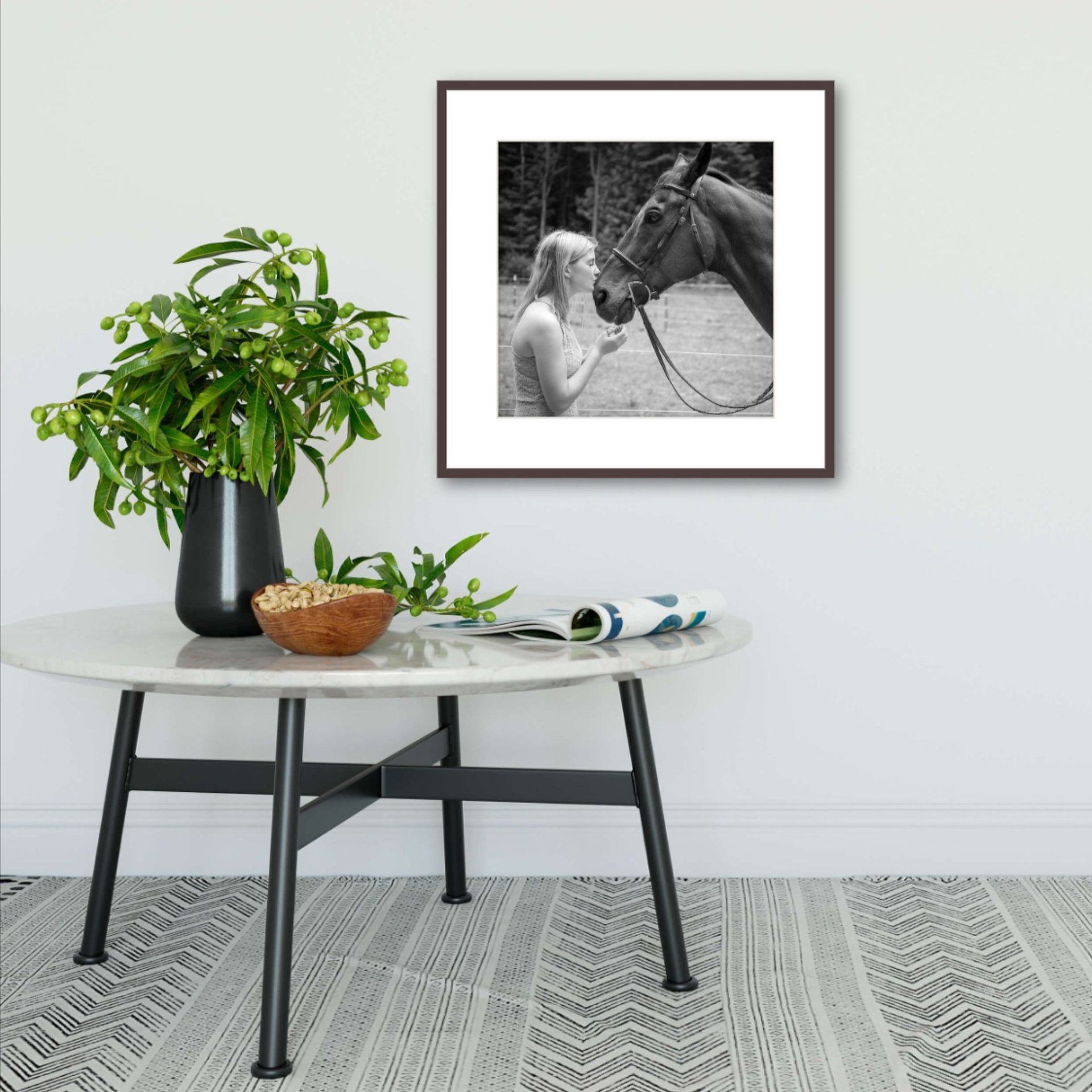 Small table beneath a framed black-and-white photo of a Carmel High School senior with her horse on a white wall.