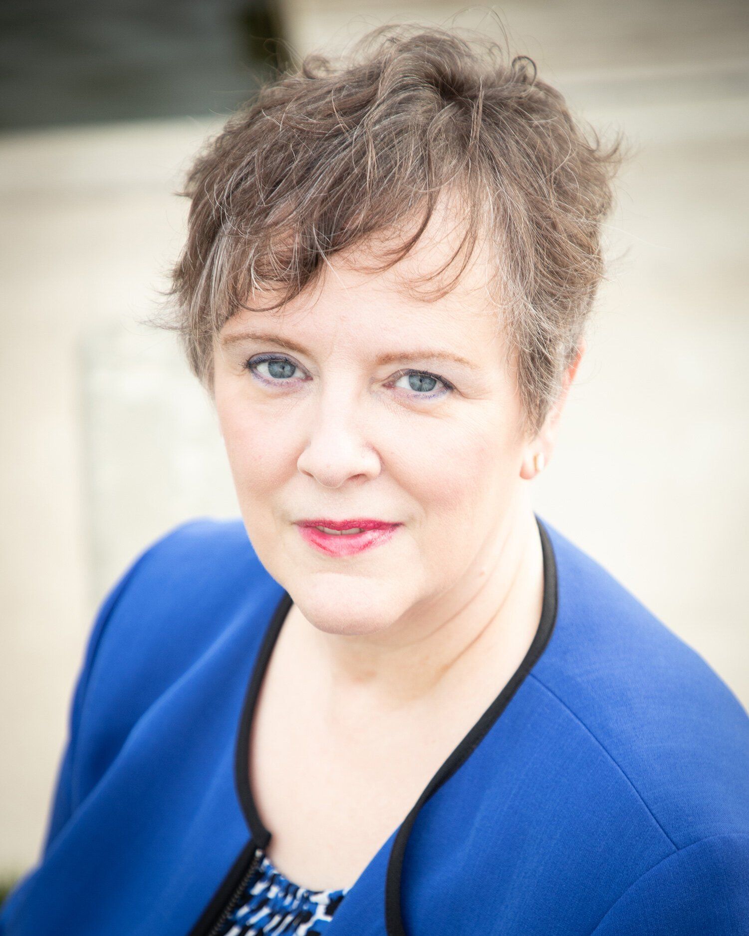 Headshot in Westfield of a person in a blue jacket with short brown hair, looking at the camera against a soft background