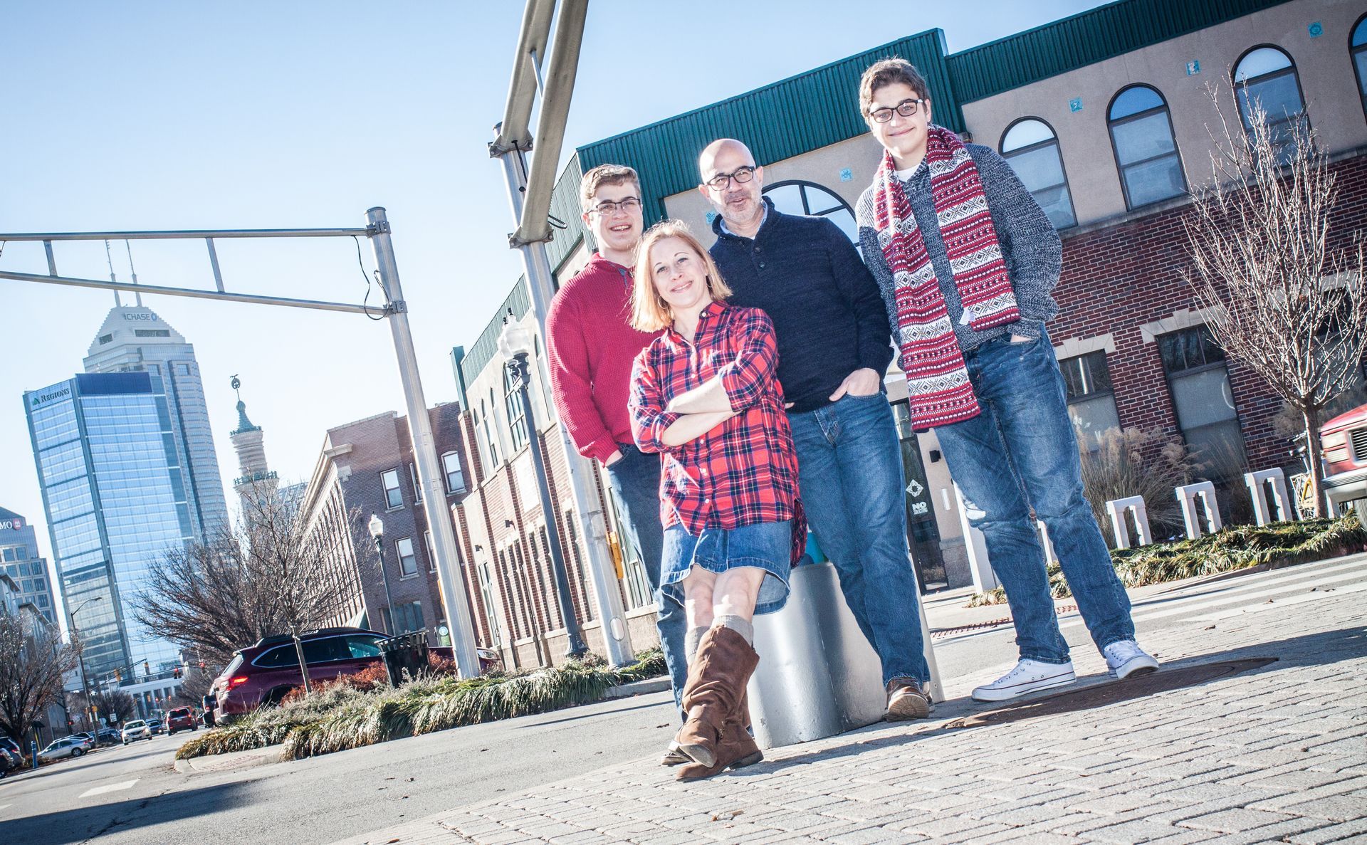 Family of rour people standing on a city sidewalk in front of a brick building on a sunny day in Indianapolis.