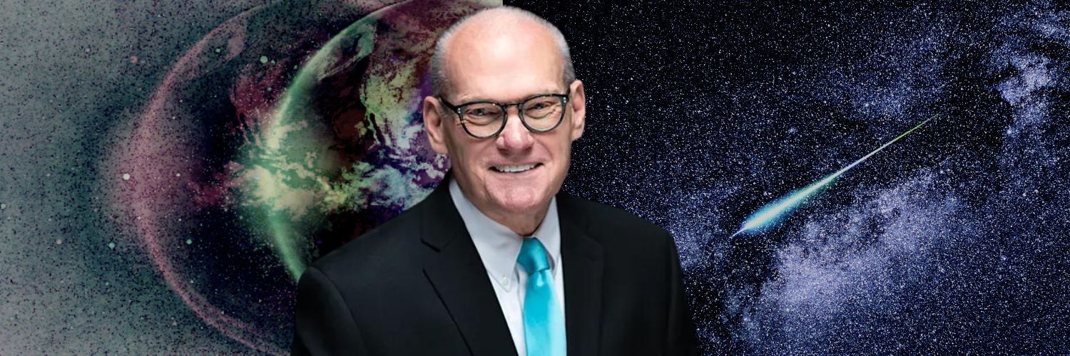 A man in a suit and tie is standing in front of a galaxy.