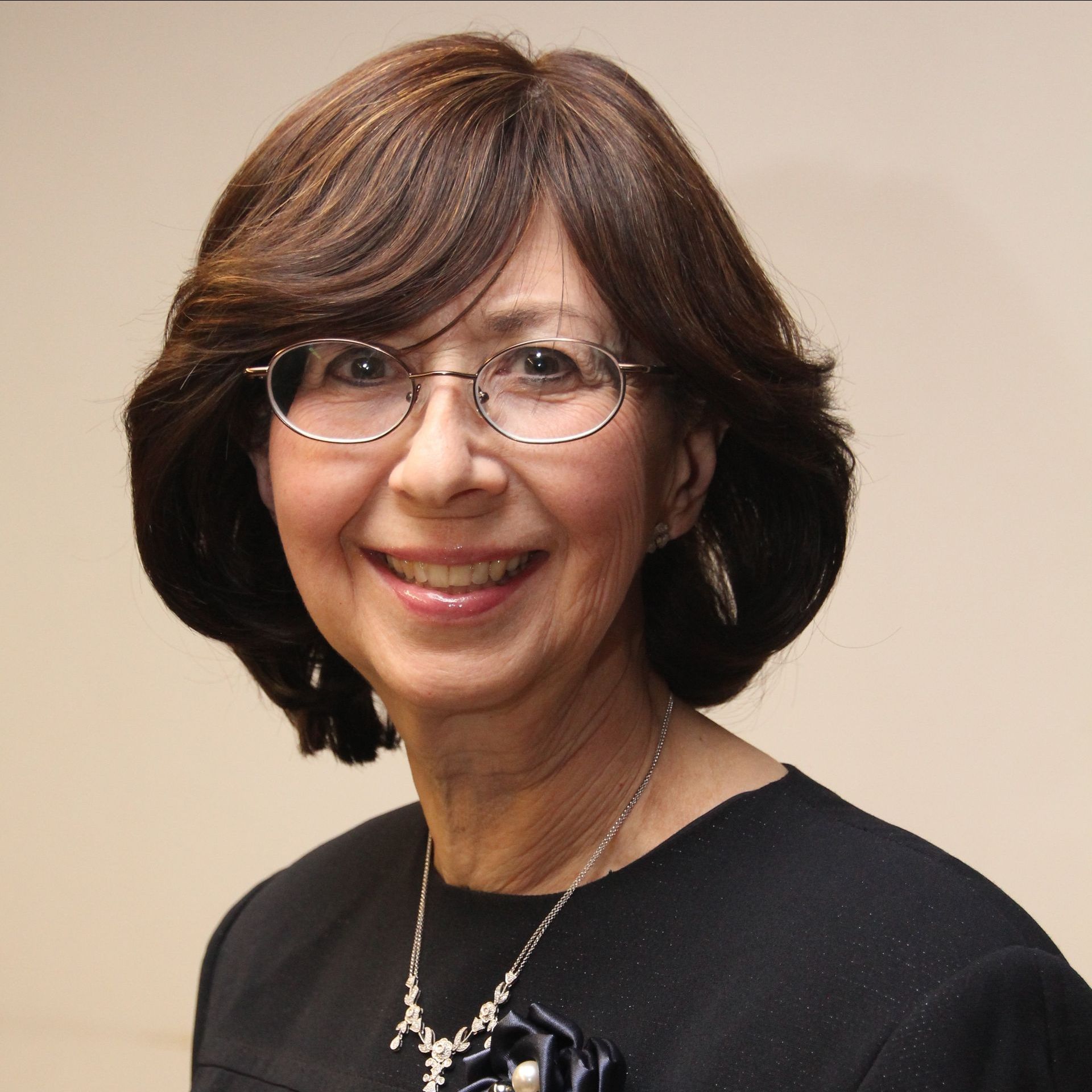 A woman wearing glasses and a black shirt smiles for the camera