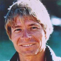 A close up of John Denver with a smile on his face.
