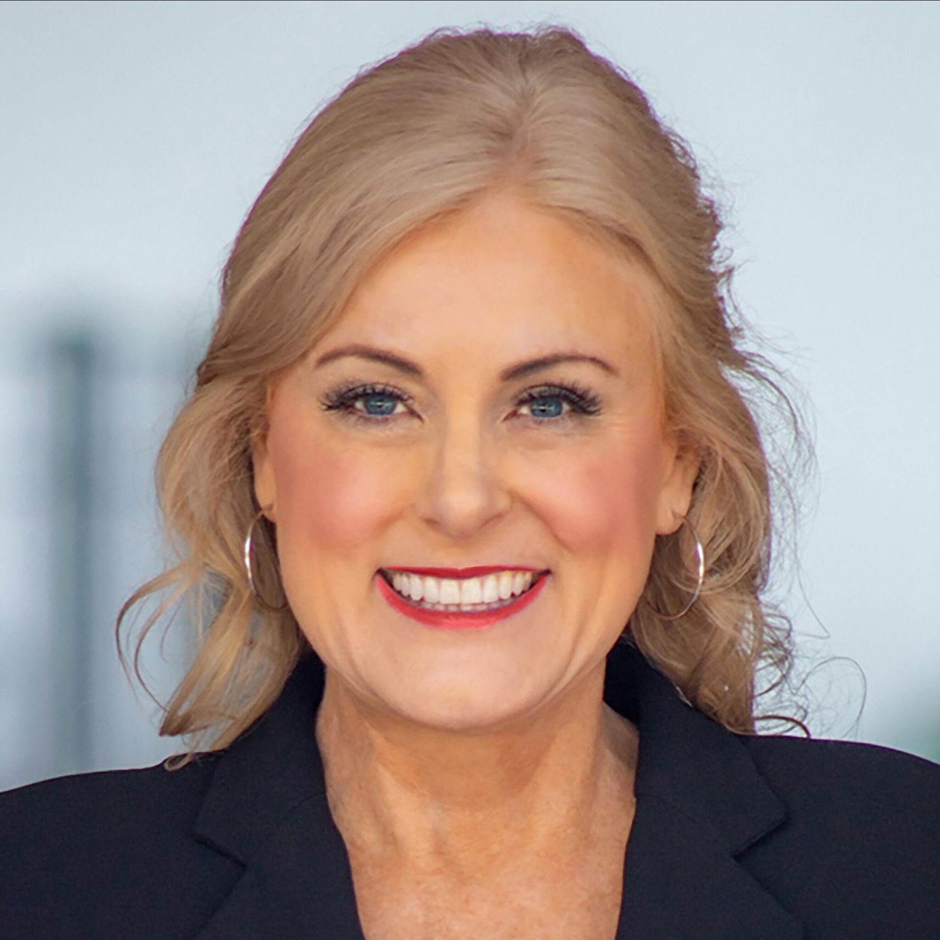 A woman in a black jacket is smiling for the camera
