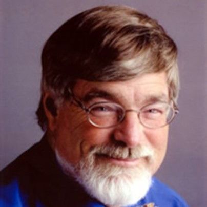 A man with glasses and a beard is wearing a blue shirt