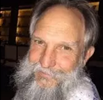 A man with a beard and mustache is looking at the camera.