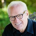A man wearing glasses and a black shirt is smiling for the camera.