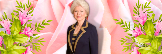 A woman in a suit is standing in front of pink flowers