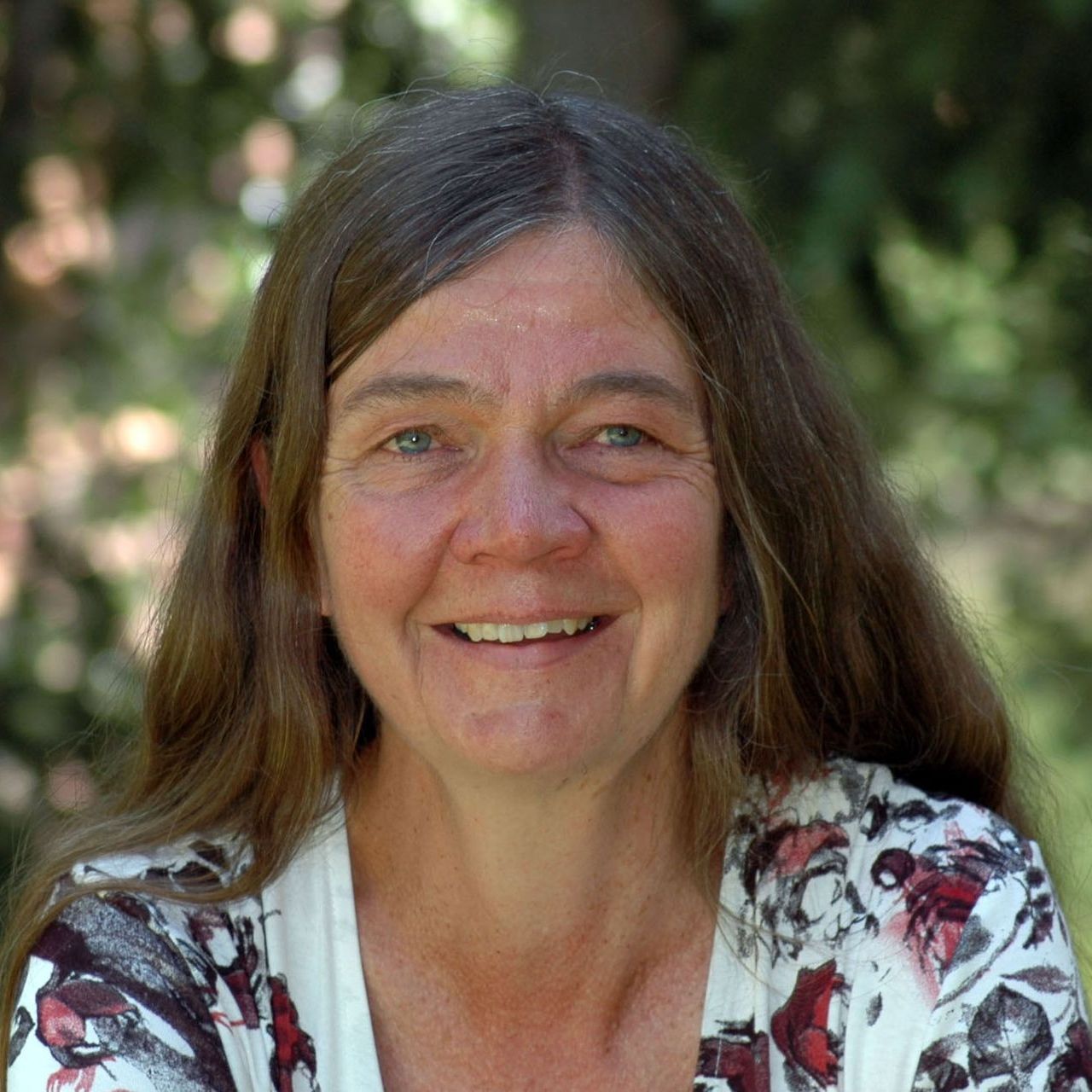 A woman with long brown hair is smiling for the camera