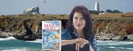 A woman is holding a book in front of a cliff overlooking the ocean.