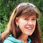 A woman wearing sunglasses and earrings is smiling for the camera.