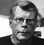 A black and white photo of a man wearing glasses and a black shirt.