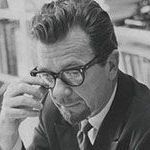 A black and white photo of a man wearing glasses and a suit and tie.