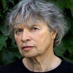 A woman with gray hair is wearing a black shirt and looking at the camera.