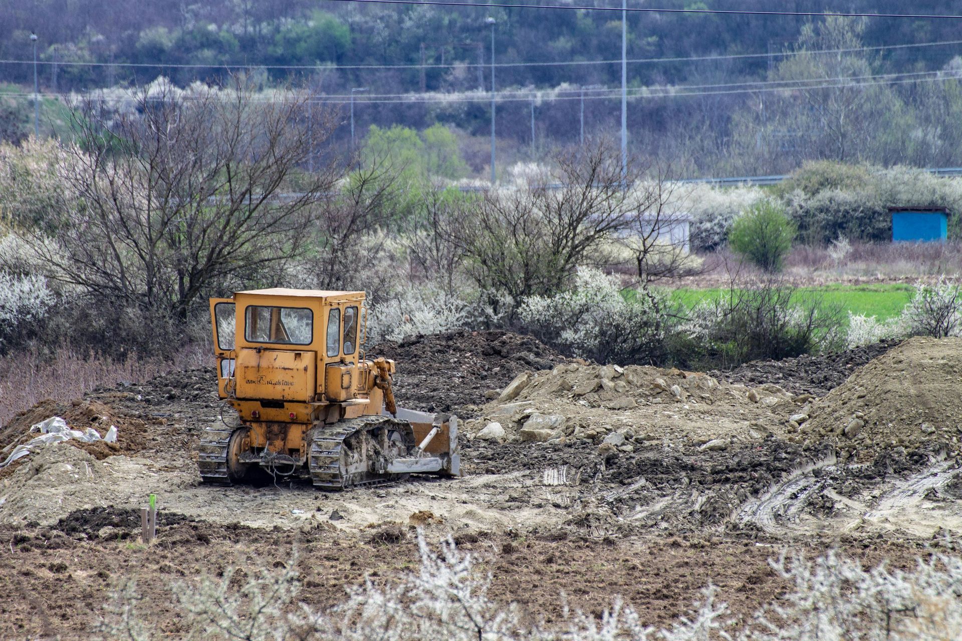 A yellow bulldozer is driving through a dirt field.