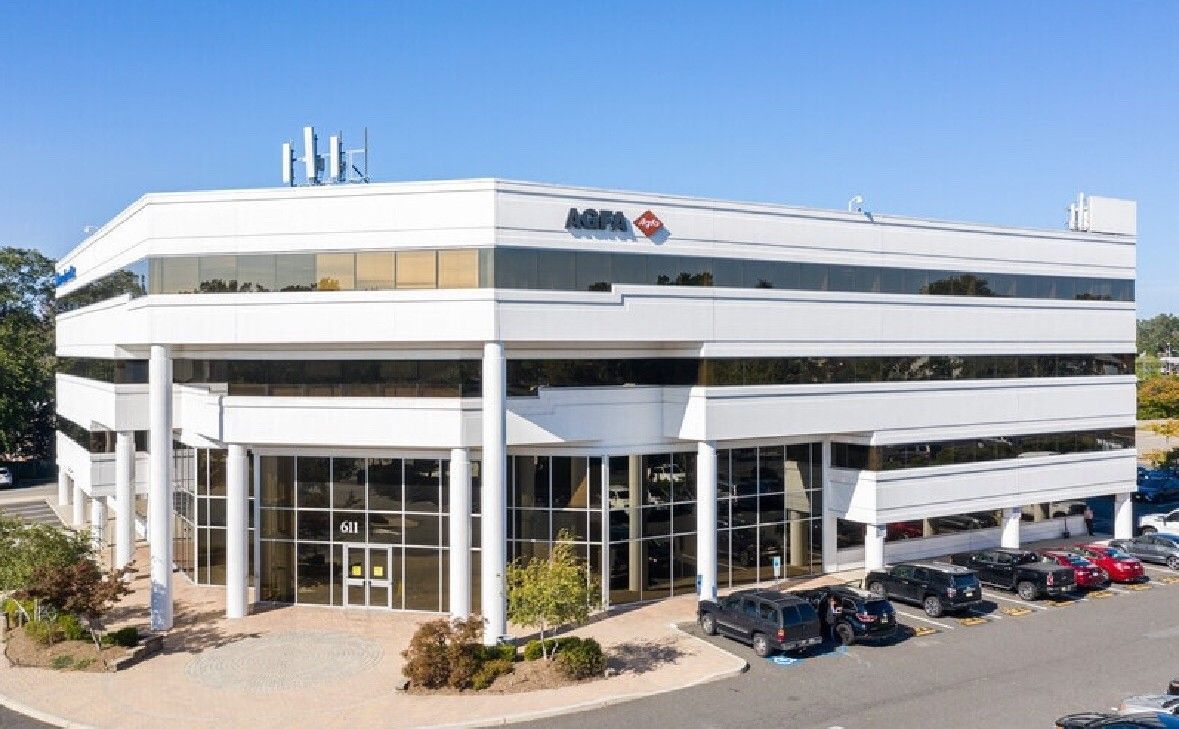 White office building with glass windows and parking lot.
