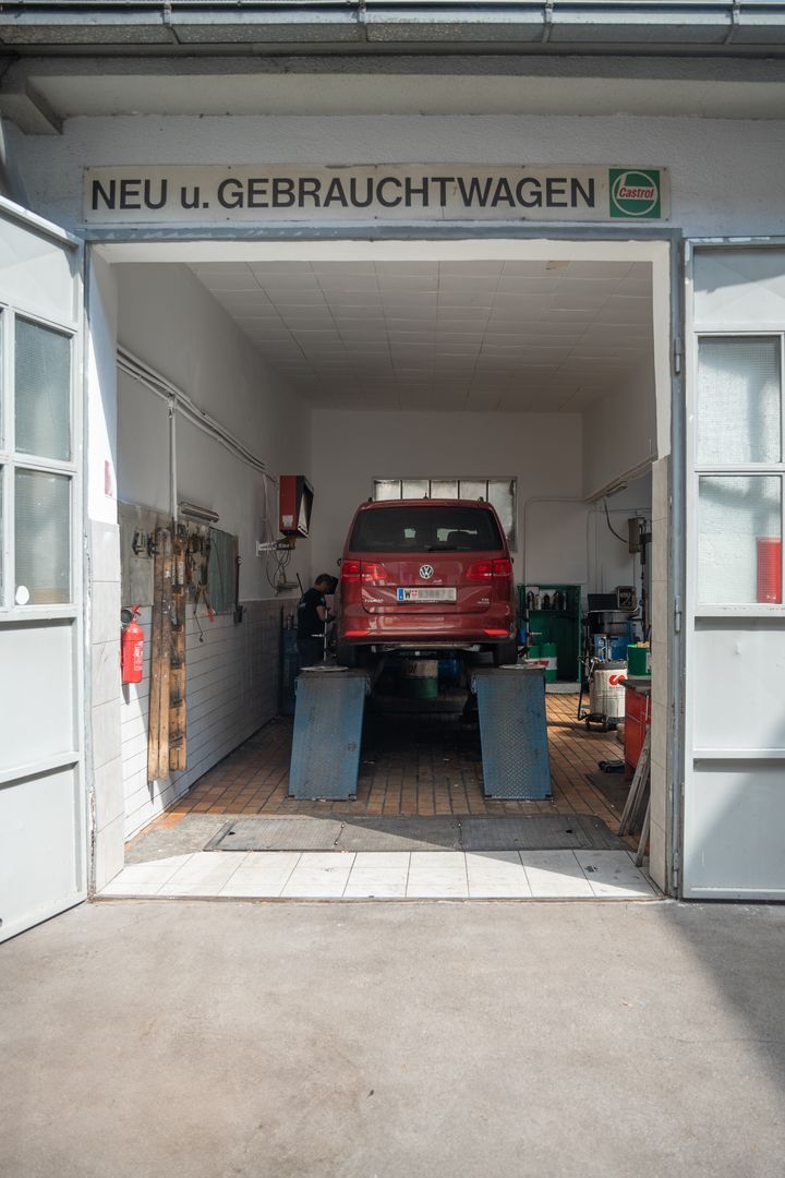 Ein rotes Auto steht auf einer Hebebühne in einer Garage.