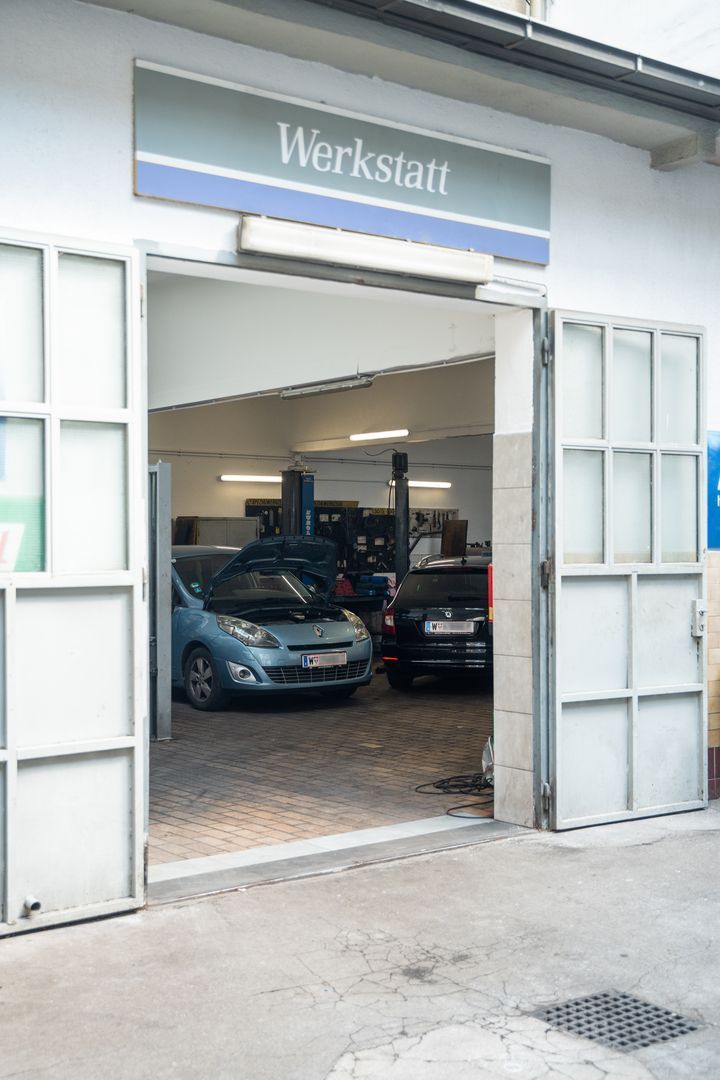 Zwei Autos stehen mit geöffneten Türen in einer Garage.