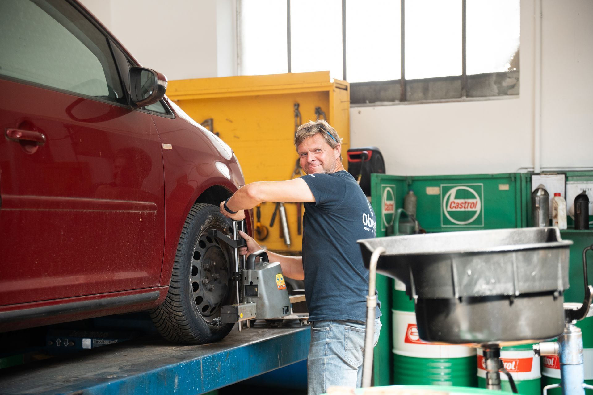 Ein Mann arbeitet in einer Garage an einem roten Auto.