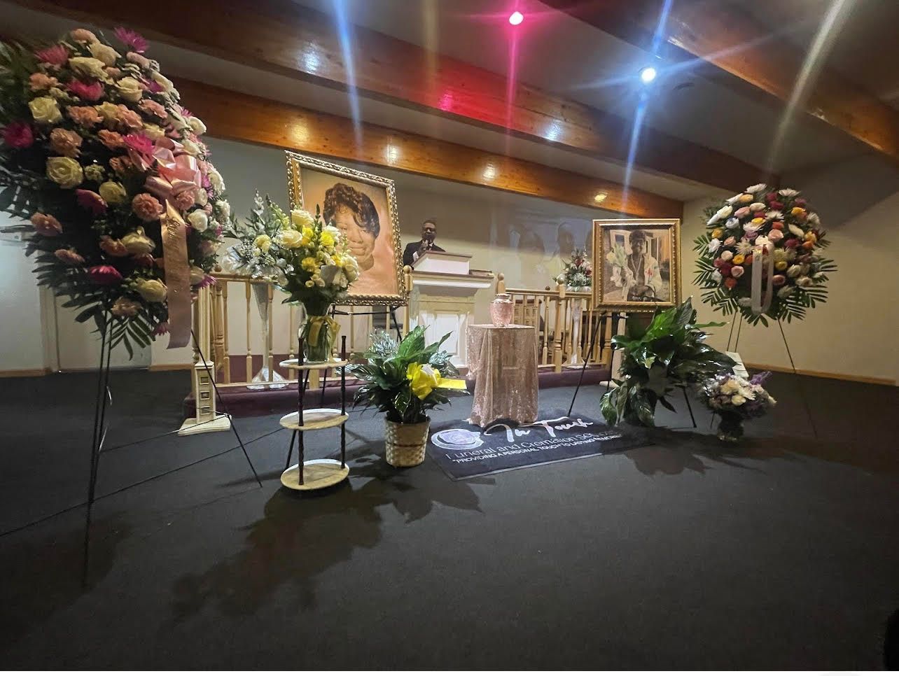 Floral-decorated stage with an altar, candles, and plants in a banquet hall