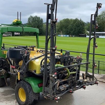 A green and yellow tractor is parked in front of a field