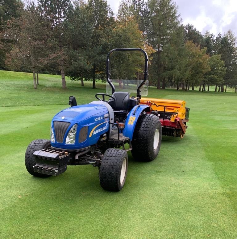 A blue tractor is parked on a lush green field