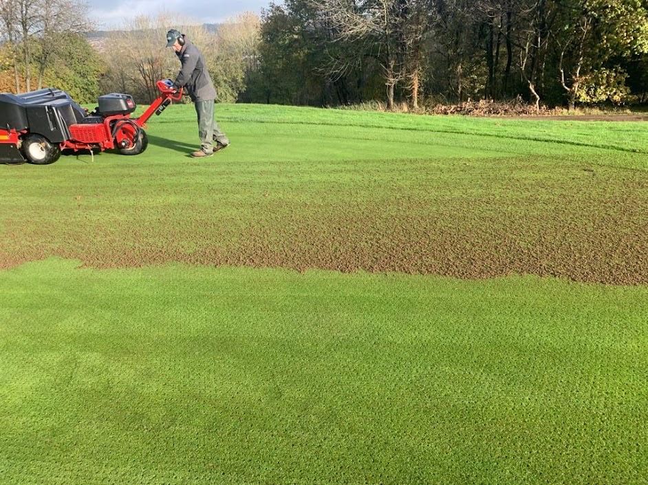 A man is using a lawn mower on a lush green field.