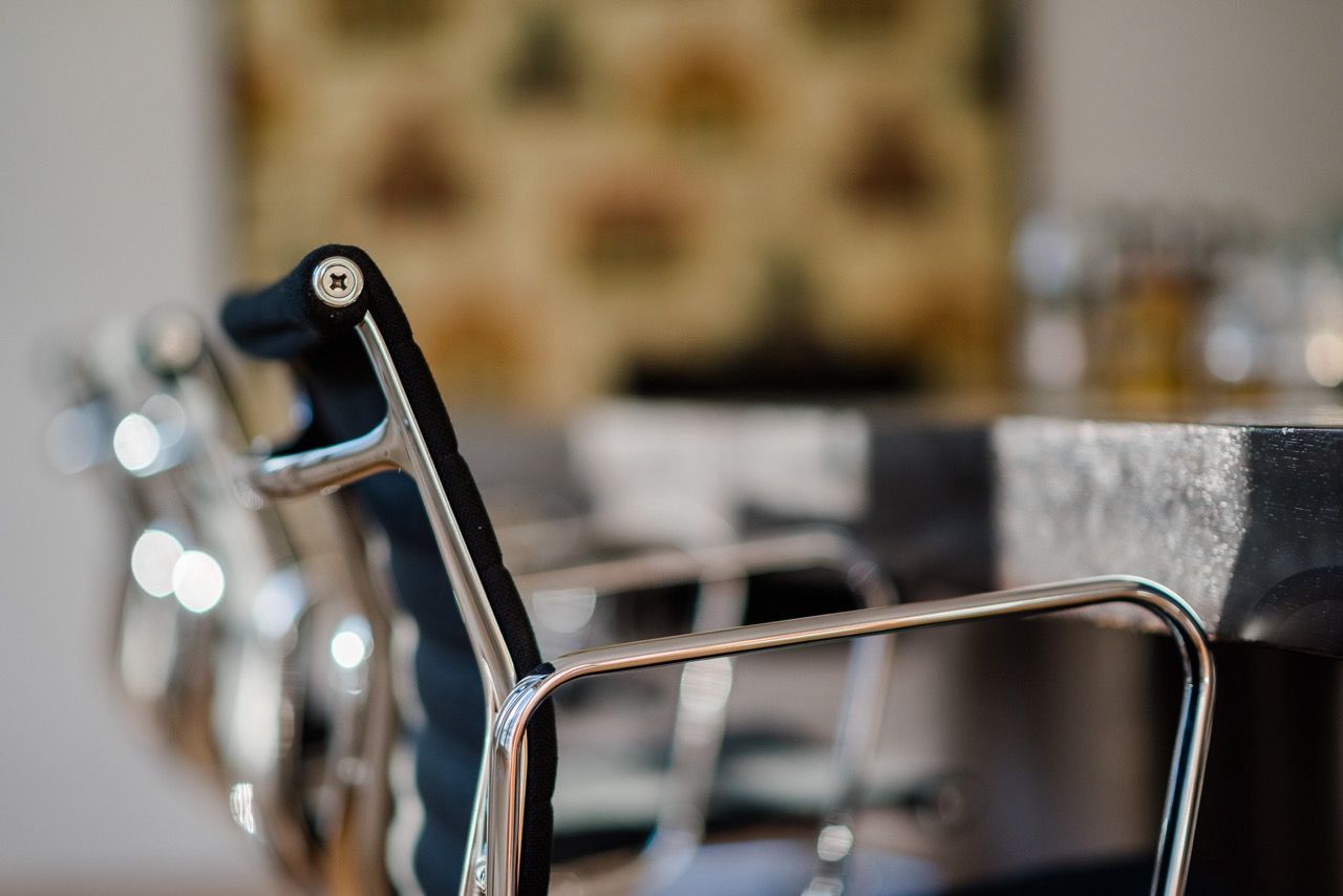 Nahaufnahme eines schwarzen Metallstuhls in einem verschwommenen, modernen Café- oder Restaurantinterieur