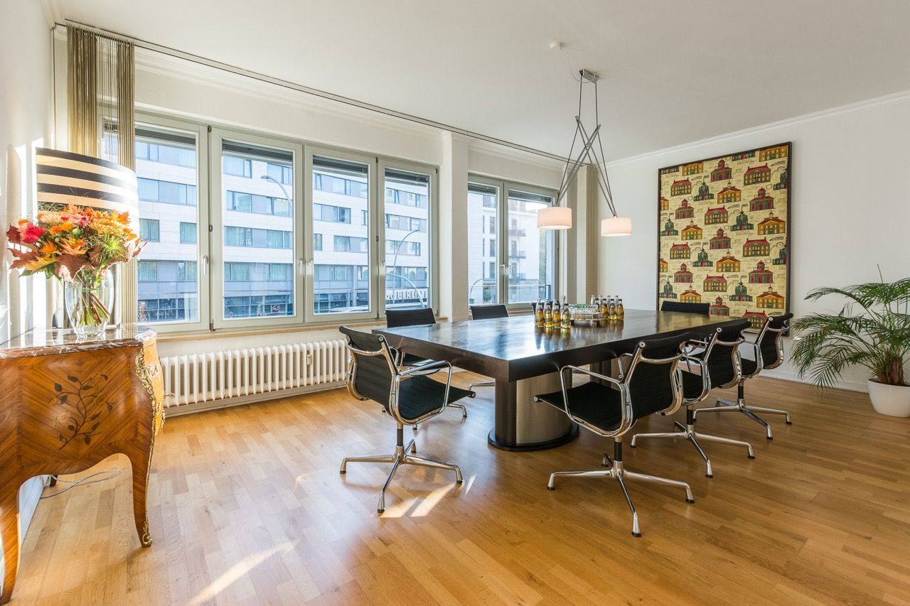 Moderner Konferenzraum mit langem Tisch, schwarzen Stühlen, großen Fenstern und Holzboden
