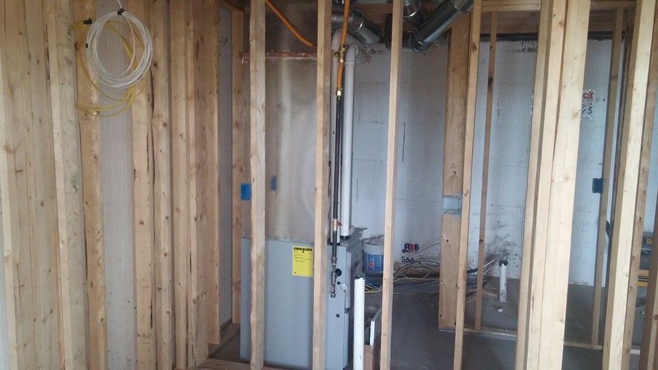 Exposed interior wall framing with electrical wiring and HVAC ducts under construction