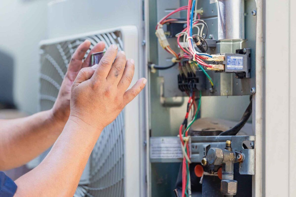Technician adjusting exposed wiring inside an electrical panel, hands near circuit components.