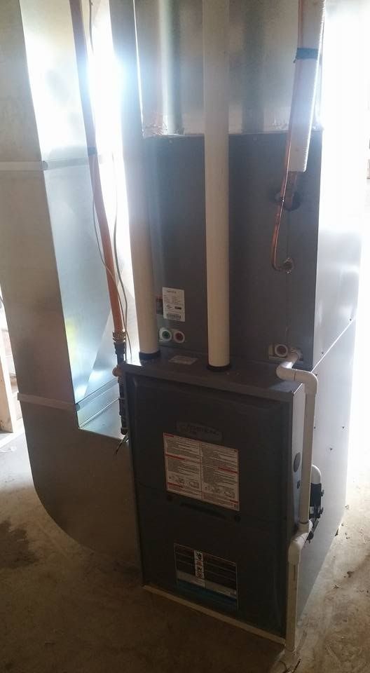 Furnace unit with exposed copper pipes and ductwork in a basement or utility closet.