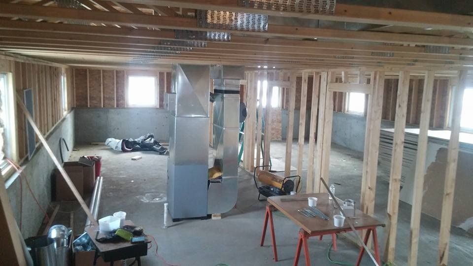 Partially built room with exposed wood framing, drywall, ladders, and construction tools inside.