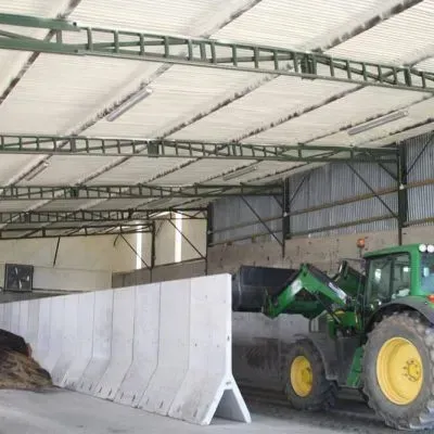 A green and yellow tractor is parked in a warehouse