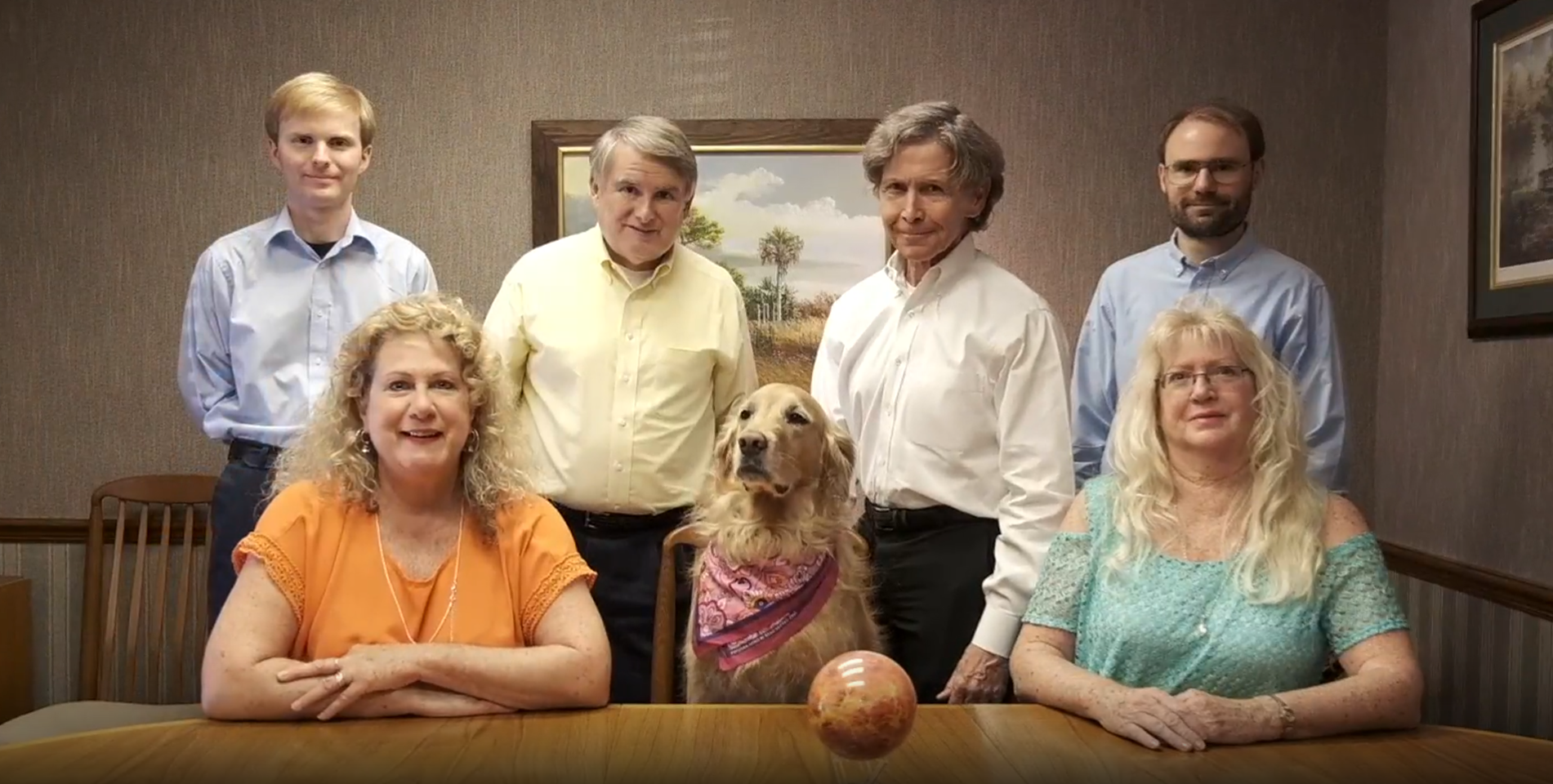 Family portrait with golden retriever and floating orb. People smile in front of a painting.
