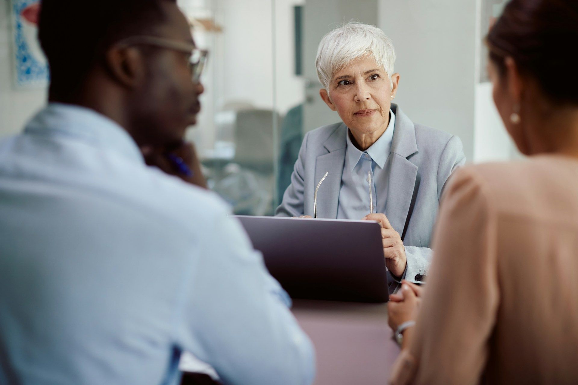 A financial advisor meeting with a couple at a table; the advisor is looking intently.