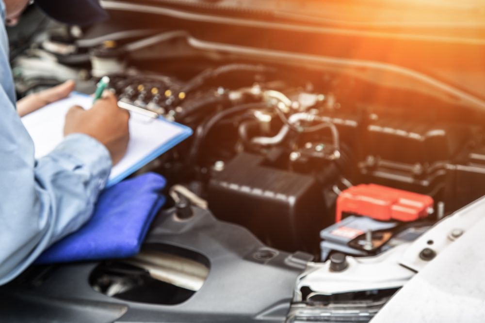 A Mechanic Is Writing On A Clipboard While Looking Under The Hood Of A Car — Manning Smash & Auto Repairs In Wingham, NSW