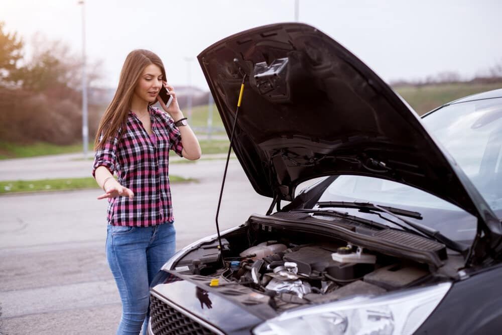 A Woman Is Talking On A Cell Phone Next To A Broken Down Car — Manning Smash & Auto Repairs In Wingham, NSW