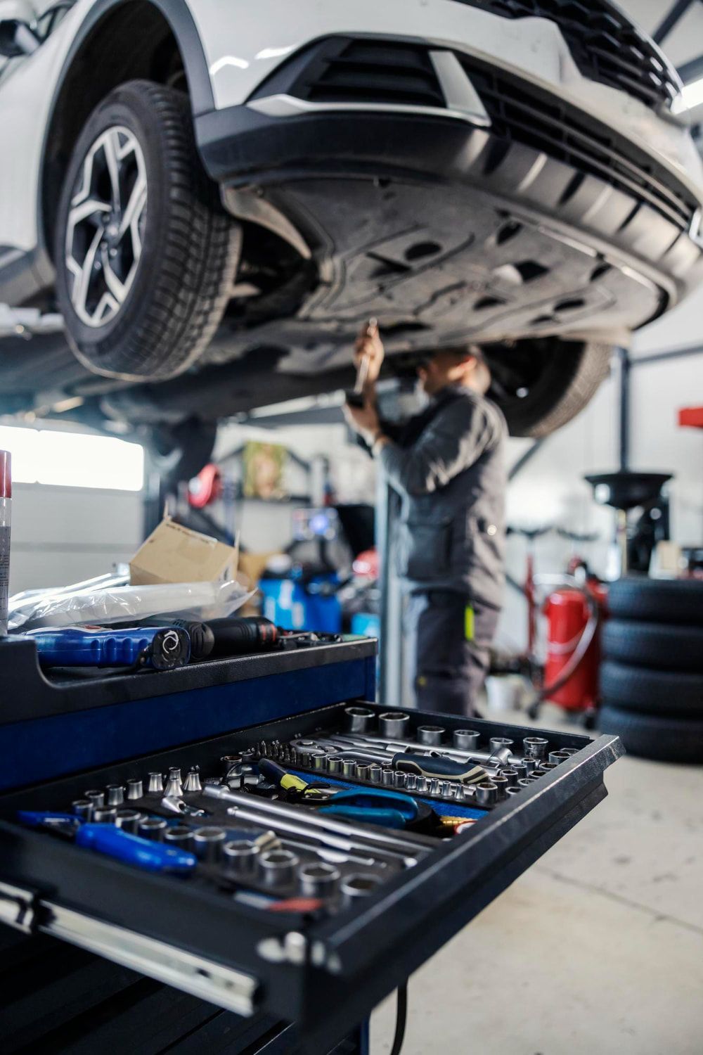 A Man Is Working Under A Car In A Garage — Manning Smash & Auto Repairs In Wingham, NSW